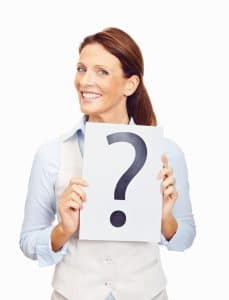 Smiling mature business woman holding a question mark sign isolated against white background